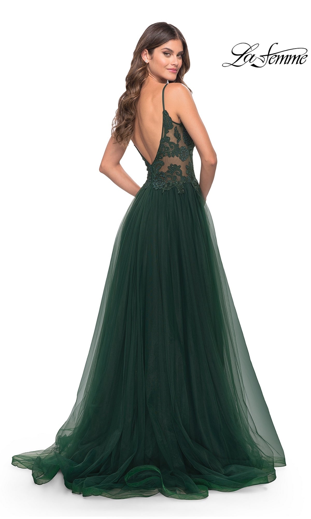 Woman wearing the Lace-Bodice Long Tulle Prom Dress: La Femme 31507, featuring a dark green lace bodice, thin straps, and open back, stands elegantly and looks over her shoulder in this formal gown.